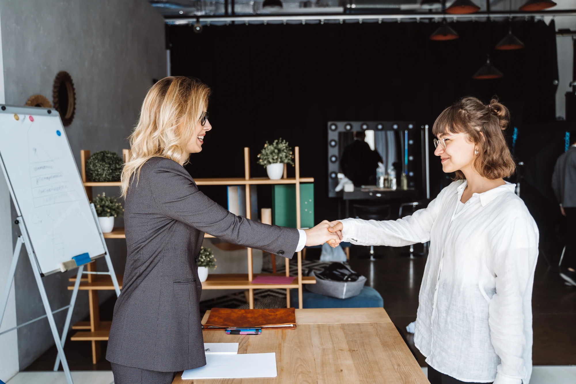 two-businesswomen-shaking-hands-office